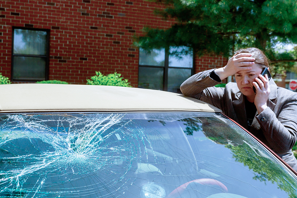 Woman making a phone call next to damaged car after a car accident